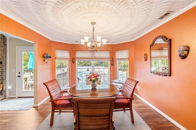 dining room featuring wood-type flooring, crown molding, and a chandelier