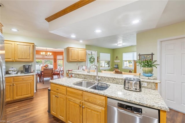 kitchen with appliances with stainless steel finishes, dark hardwood / wood-style flooring, sink, a center island with sink, and a notable chandelier