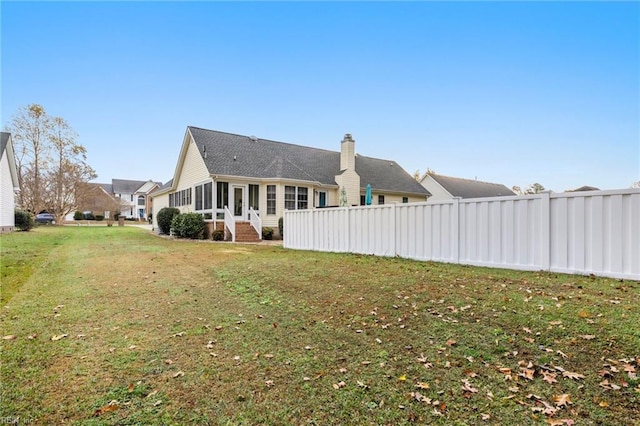 back of property with a sunroom and a yard