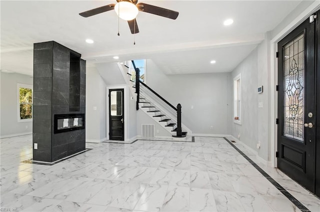 entryway with a tile fireplace, ceiling fan, and beamed ceiling