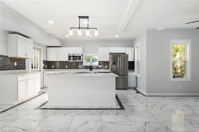 kitchen with white cabinets, decorative backsplash, a center island, and stainless steel appliances