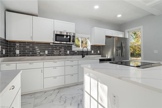 kitchen featuring white cabinetry, sink, tasteful backsplash, light stone counters, and appliances with stainless steel finishes