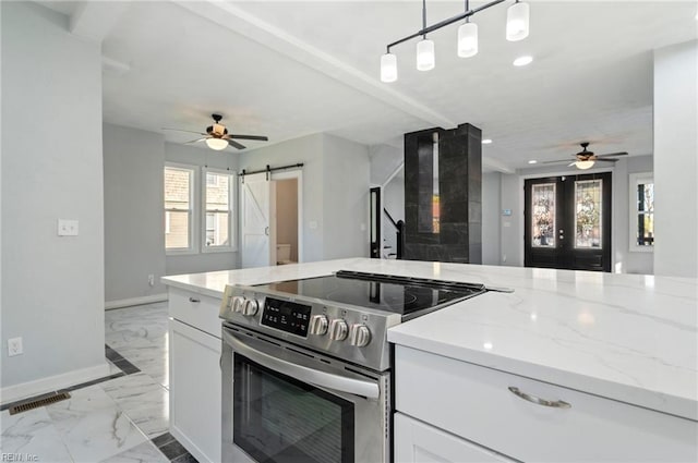 kitchen with light stone counters, stainless steel range with electric stovetop, a barn door, decorative light fixtures, and white cabinets