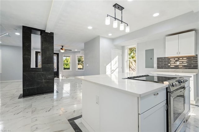 kitchen with ceiling fan, a kitchen island, plenty of natural light, stainless steel electric range, and white cabinets