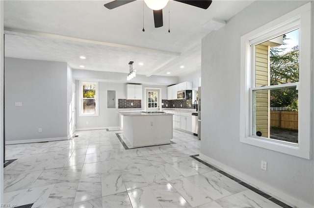 kitchen with a center island, white cabinets, hanging light fixtures, decorative backsplash, and beamed ceiling