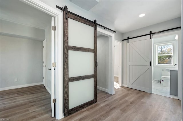 interior space with a barn door and wood-type flooring