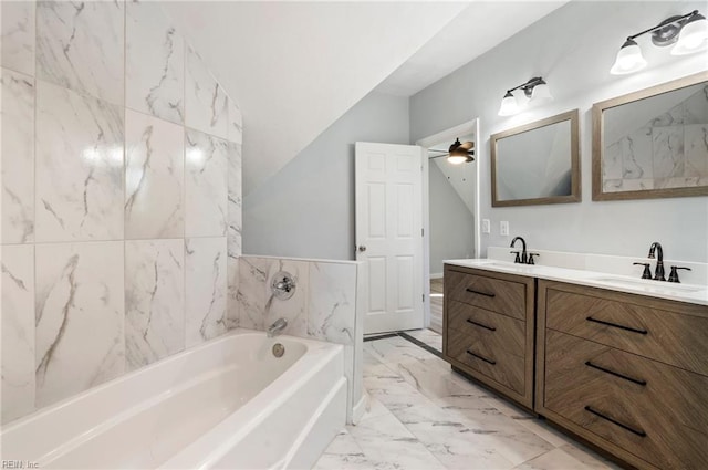 bathroom featuring ceiling fan, a bath, lofted ceiling, vanity, and tile walls