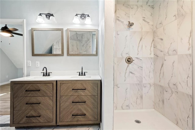 bathroom with a tile shower, ceiling fan, and vanity