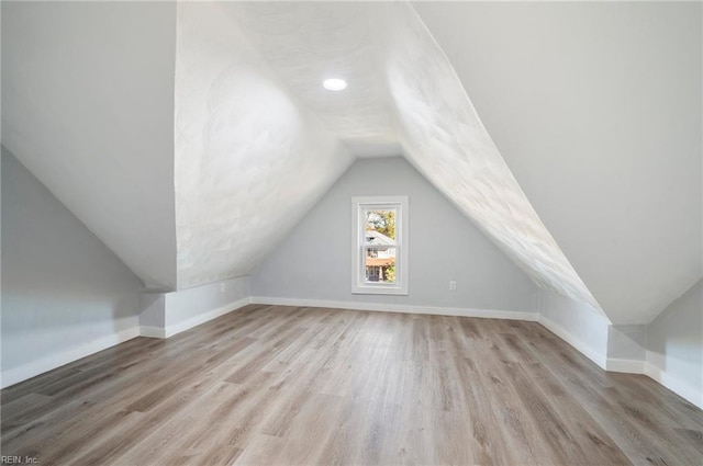 additional living space featuring light hardwood / wood-style floors and vaulted ceiling