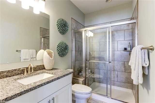 bathroom featuring tile patterned floors, vanity, a shower with shower door, and toilet