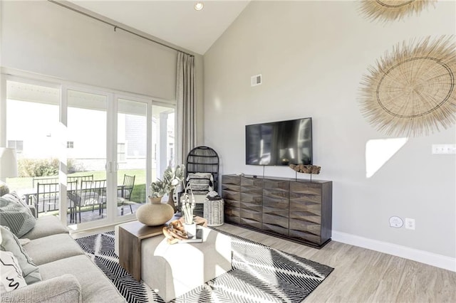 living room featuring high vaulted ceiling and light wood-type flooring