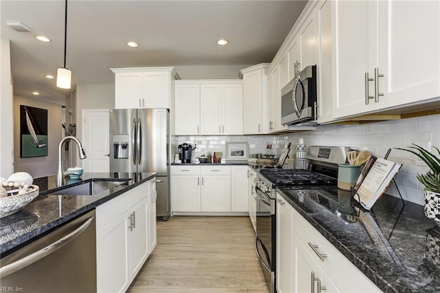 kitchen with white cabinetry, sink, decorative light fixtures, and appliances with stainless steel finishes