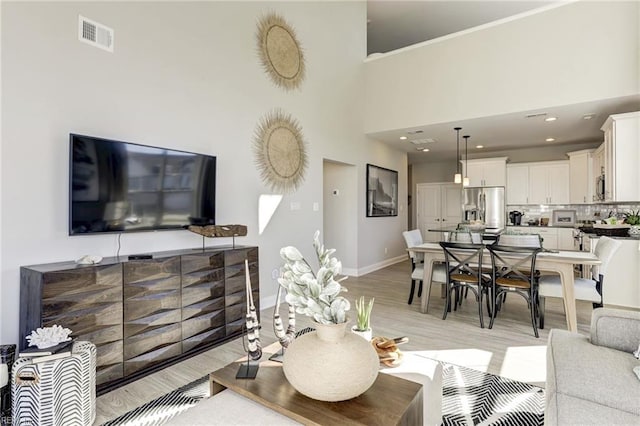 living room with a towering ceiling and light hardwood / wood-style flooring