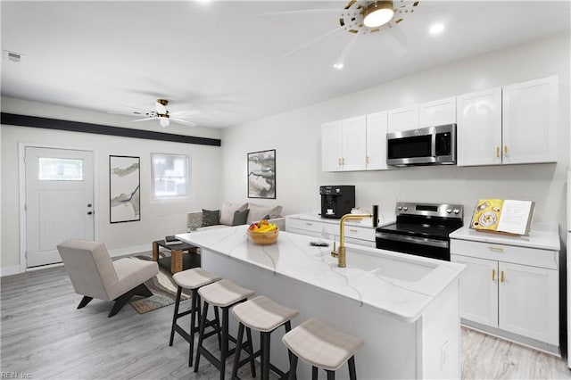 kitchen featuring a kitchen breakfast bar, white cabinets, an island with sink, and stainless steel appliances