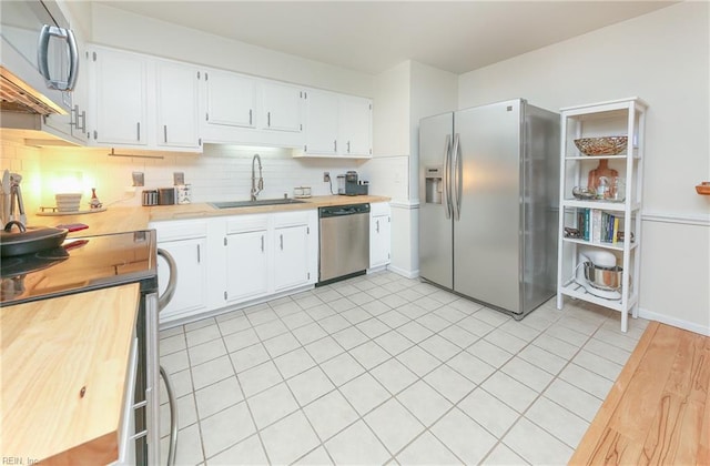 kitchen featuring backsplash, sink, white cabinetry, butcher block counters, and stainless steel appliances