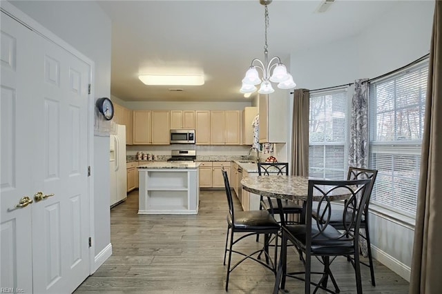 kitchen featuring stainless steel appliances, an inviting chandelier, light hardwood / wood-style flooring, decorative light fixtures, and a kitchen island