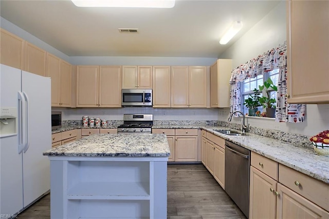 kitchen with sink, appliances with stainless steel finishes, light brown cabinetry, a kitchen island, and light wood-type flooring