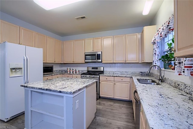 kitchen with sink, dark hardwood / wood-style floors, a kitchen island, light stone counters, and stainless steel appliances