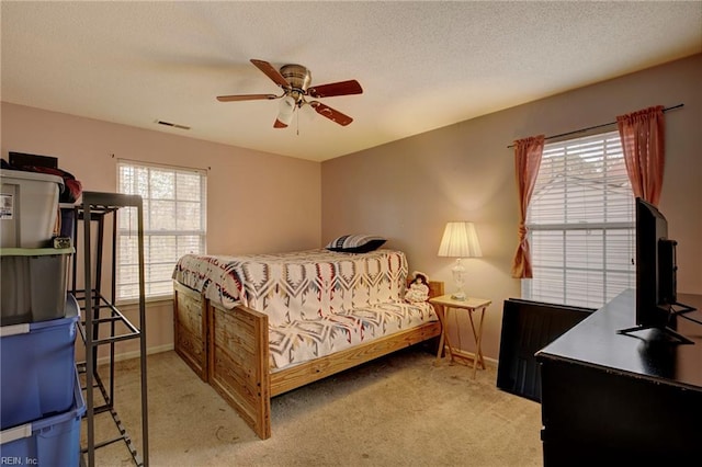 carpeted bedroom featuring ceiling fan and a textured ceiling