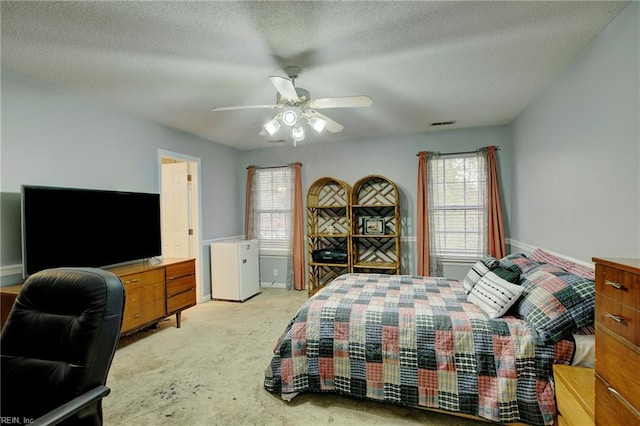 carpeted bedroom featuring ceiling fan and a textured ceiling