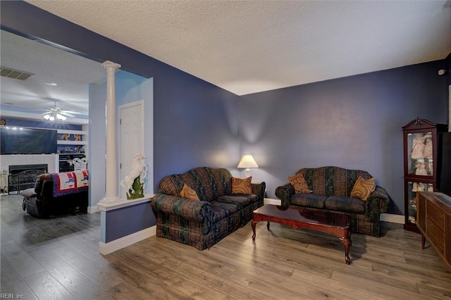 living room featuring hardwood / wood-style floors, a textured ceiling, decorative columns, and ceiling fan