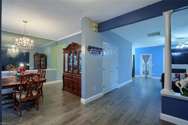 dining space with ornate columns, ceiling fan with notable chandelier, a textured ceiling, dark wood-type flooring, and beam ceiling