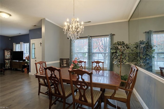 dining room with dark hardwood / wood-style flooring, ornamental molding, and a notable chandelier