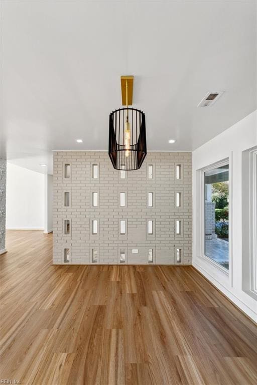 unfurnished living room with light wood-type flooring and brick wall