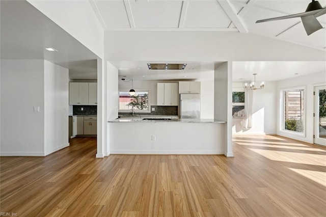 unfurnished living room with light hardwood / wood-style flooring, lofted ceiling with beams, ceiling fan with notable chandelier, and sink