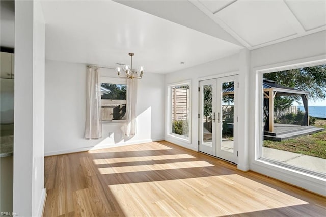 interior space with a chandelier, vaulted ceiling, wood-type flooring, and french doors