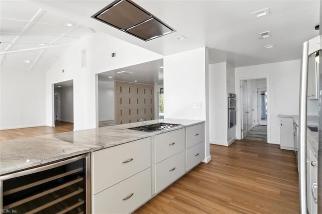 kitchen featuring white cabinets, light stone counters, stainless steel appliances, and beverage cooler