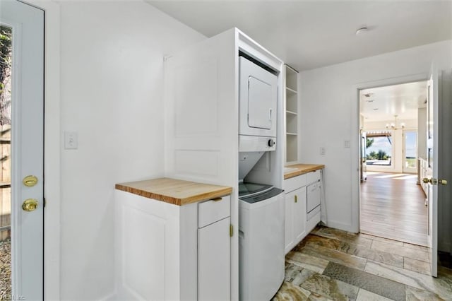 kitchen featuring white cabinetry, butcher block counters, light hardwood / wood-style flooring, and stacked washer and clothes dryer