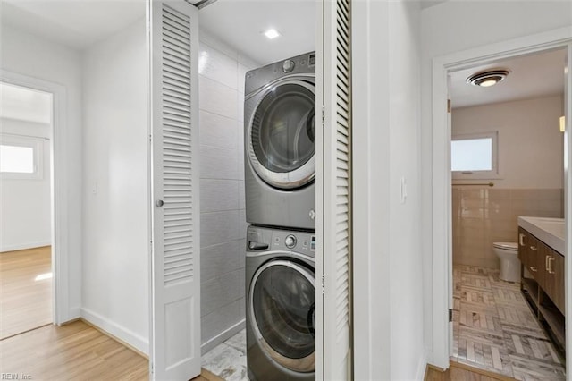 washroom featuring stacked washer / drying machine and plenty of natural light