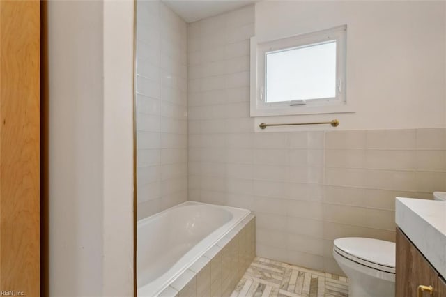 bathroom featuring tiled tub, tile patterned flooring, vanity, and toilet