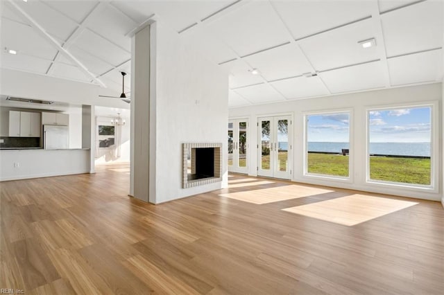 unfurnished living room with ceiling fan, a fireplace, and light hardwood / wood-style flooring