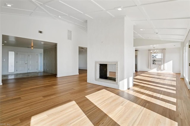 unfurnished living room with a fireplace, wood-type flooring, lofted ceiling, and a notable chandelier