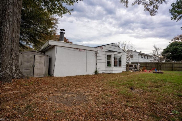 back of house with a lawn and a storage shed