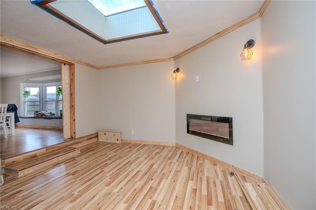 unfurnished living room with a skylight, ornamental molding, and hardwood / wood-style flooring