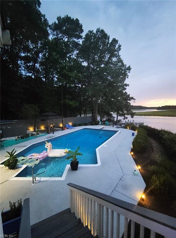 pool at dusk with a jacuzzi and a water view