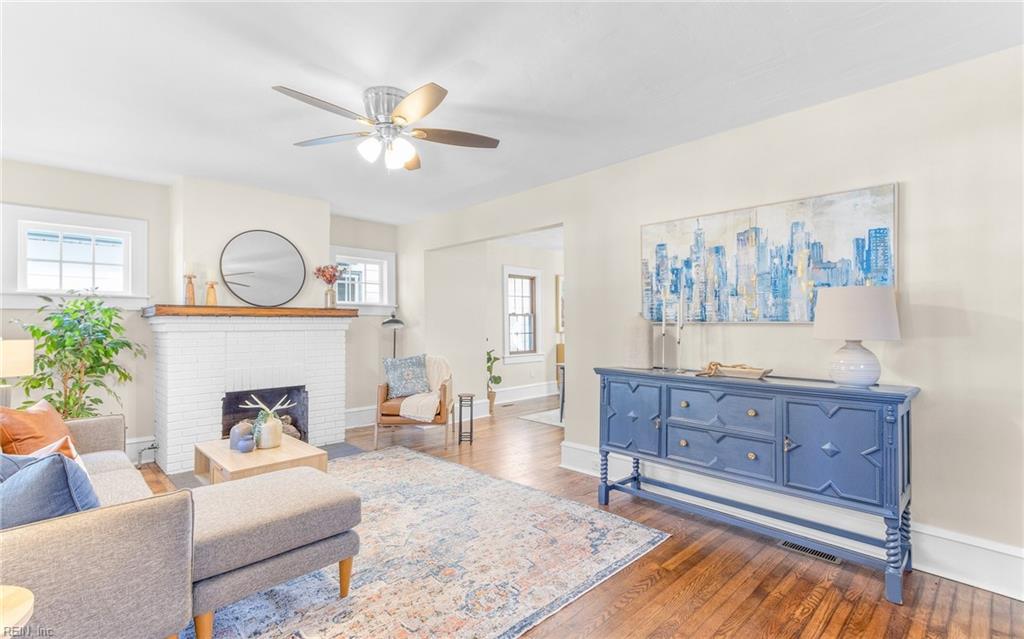 living room featuring ceiling fan, dark wood-type flooring, and a brick fireplace