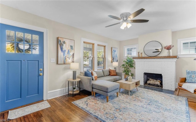 living room featuring ceiling fan, a fireplace, and dark wood-type flooring