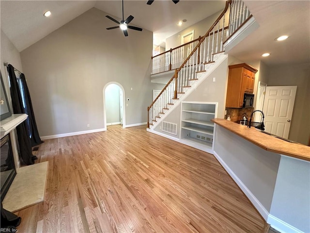 unfurnished living room featuring light hardwood / wood-style flooring, high vaulted ceiling, and ceiling fan