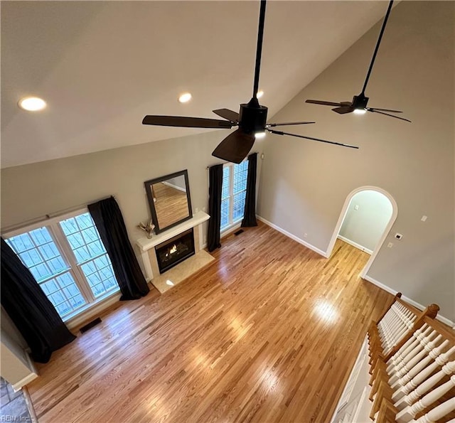 unfurnished living room featuring ceiling fan, high vaulted ceiling, and light wood-type flooring