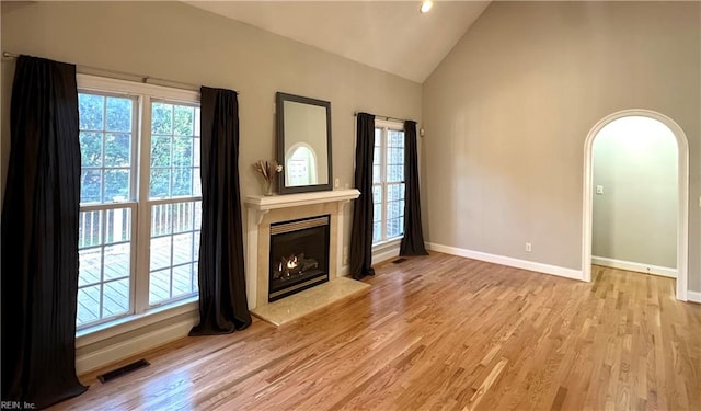 unfurnished living room with high vaulted ceiling and light hardwood / wood-style floors