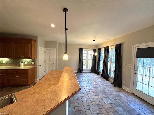 kitchen featuring decorative backsplash, sink, hanging light fixtures, and a chandelier