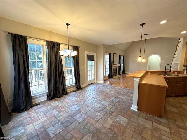 kitchen with butcher block countertops, sink, hanging light fixtures, and lofted ceiling