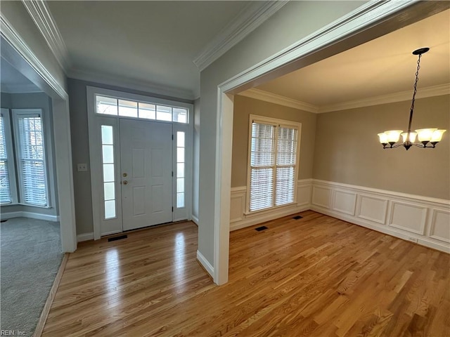 entryway with hardwood / wood-style flooring, crown molding, and a notable chandelier