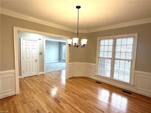 unfurnished dining area featuring a chandelier, light hardwood / wood-style flooring, and crown molding