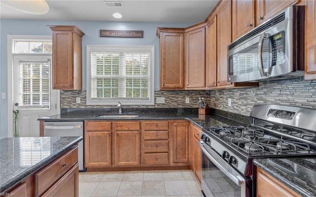 kitchen featuring tasteful backsplash, sink, dark stone counters, and appliances with stainless steel finishes