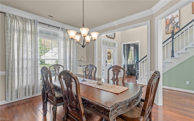 dining space featuring crown molding, hardwood / wood-style floors, and a notable chandelier